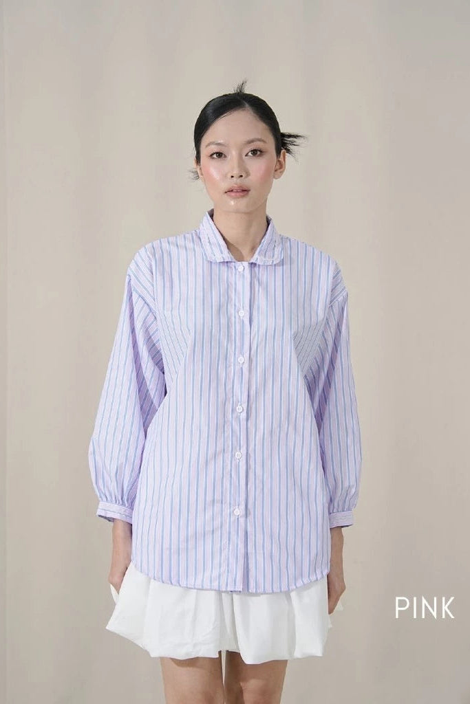 Person wearing a light pink striped shirt by Tuff Puff and white skirt on a plain background