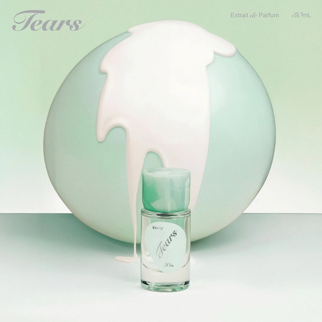 Perfume bottle labeled 'Tears' from Kitschy with a large decorative sphere in the background.