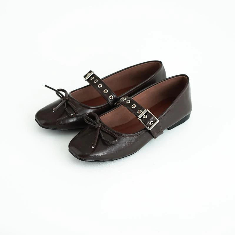 Pair of brown flatshoes with bow details and buckles by Tangerine Marche on a white background